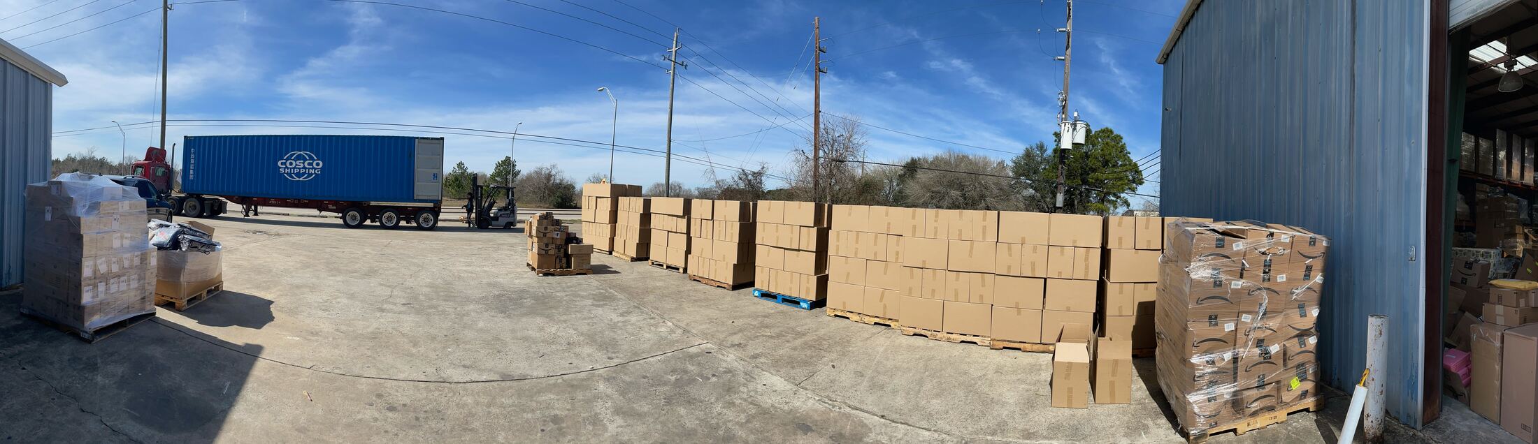 Panorama of FlexPrep's stabilized yard with a shipping container, forklift and rows of palletized cartons being handled